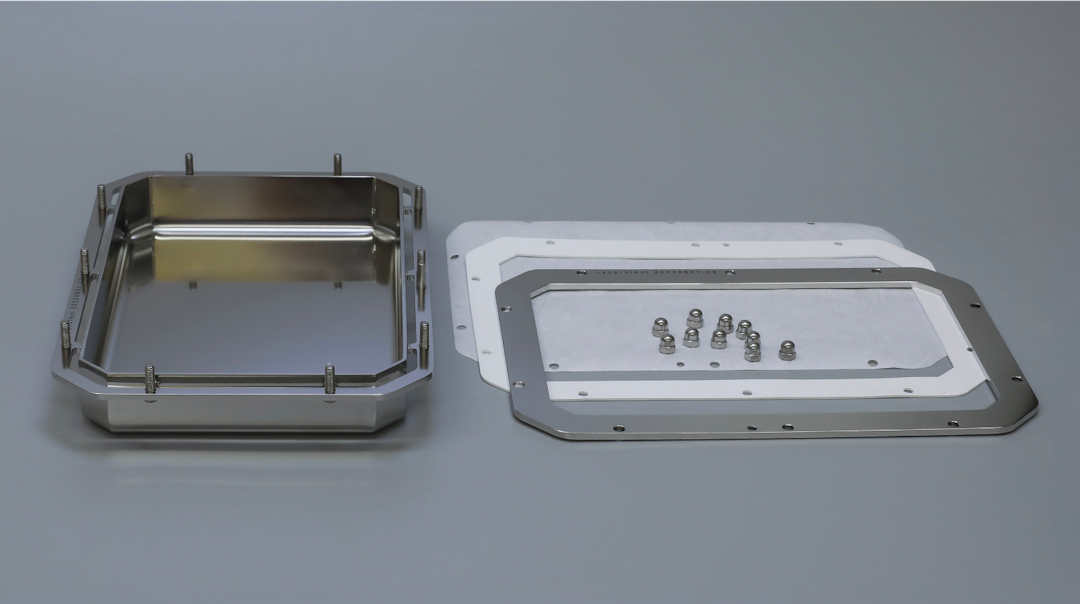 Lyoprotect Edelstahlwanne mit Komponenten. Links: Wanne; rechts: Membrane, Dichtung, Rahmen, Muttern.